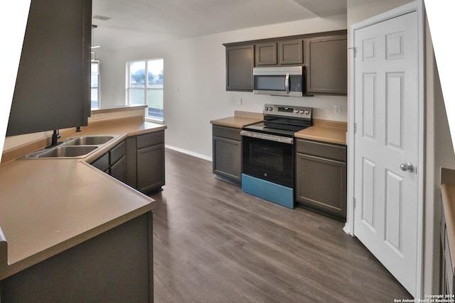 kitchen featuring appliances with stainless steel finishes, sink, dark hardwood / wood-style flooring, and dark brown cabinets