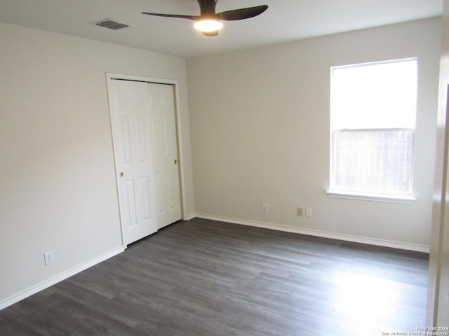 unfurnished bedroom with dark wood-type flooring, ceiling fan, and a closet