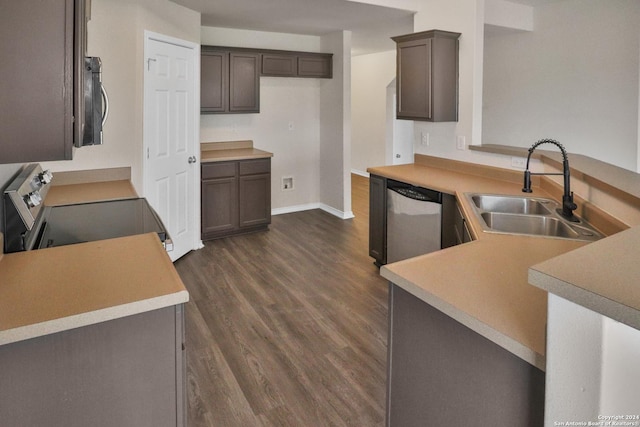 kitchen with appliances with stainless steel finishes, sink, dark brown cabinets, kitchen peninsula, and dark wood-type flooring