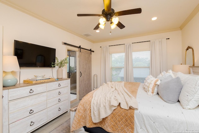 bedroom featuring light hardwood / wood-style flooring, ornamental molding, a barn door, and ceiling fan