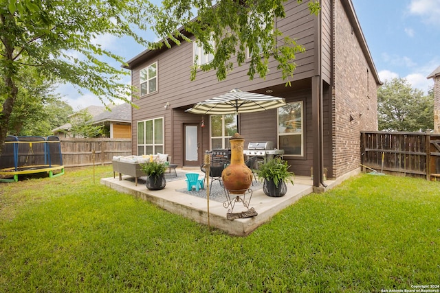 rear view of house with an outdoor living space, a lawn, a trampoline, and a patio area