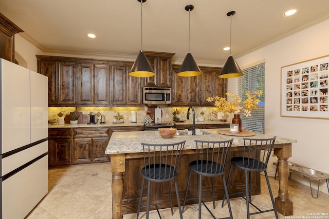 kitchen with hanging light fixtures, decorative backsplash, stainless steel appliances, and an island with sink