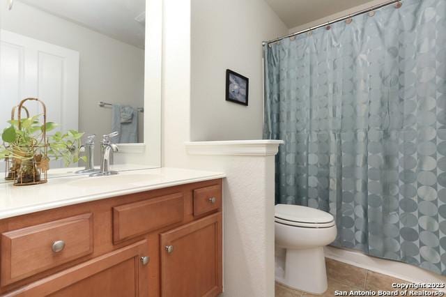 bathroom featuring tile patterned flooring, vanity, walk in shower, and toilet