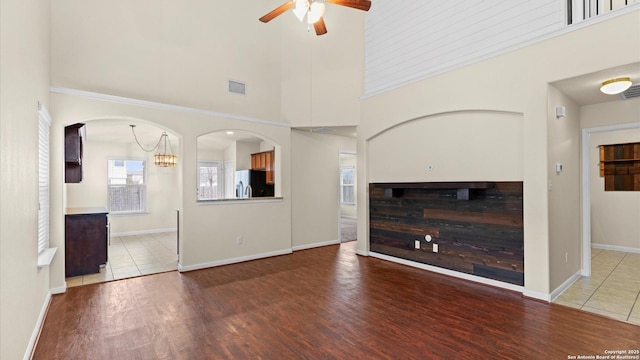 unfurnished living room featuring hardwood / wood-style flooring, a high ceiling, and ceiling fan