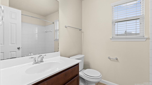 bathroom with vanity, toilet, and a tile shower