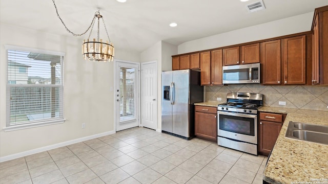 kitchen featuring sink, light tile patterned floors, appliances with stainless steel finishes, decorative backsplash, and decorative light fixtures