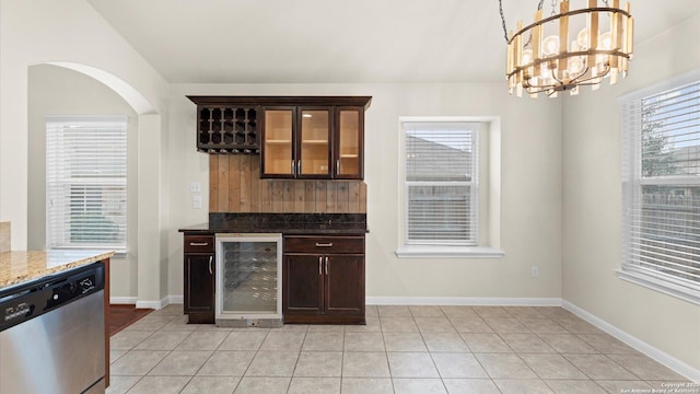 bar with pendant lighting, dark stone countertops, wine cooler, stainless steel dishwasher, and dark brown cabinets