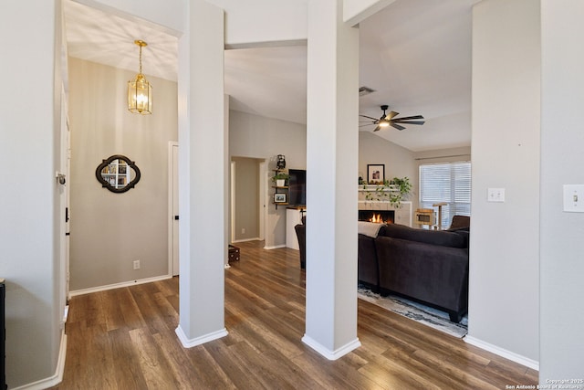 interior space featuring lofted ceiling, dark wood-type flooring, a fireplace, and ceiling fan