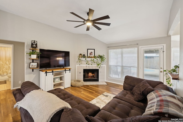 living room featuring ceiling fan, lofted ceiling, a fireplace, and hardwood / wood-style floors