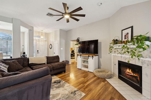 living room with vaulted ceiling, ceiling fan, a fireplace, and light hardwood / wood-style floors