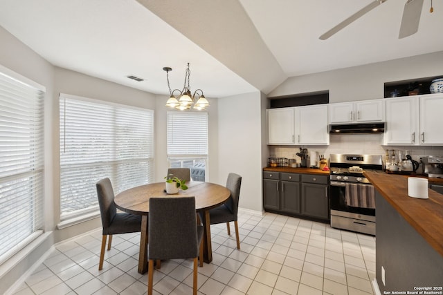 kitchen with stainless steel gas range, butcher block countertops, white cabinets, pendant lighting, and backsplash