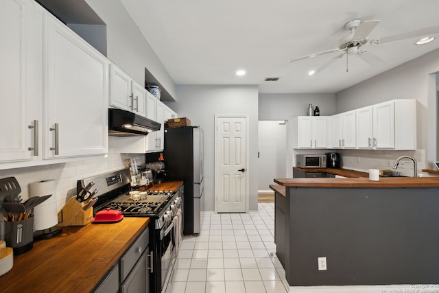 kitchen featuring white cabinetry, wood counters, appliances with stainless steel finishes, and light tile patterned floors