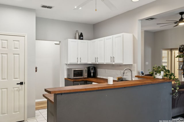 kitchen featuring white cabinetry, decorative backsplash, kitchen peninsula, and ceiling fan