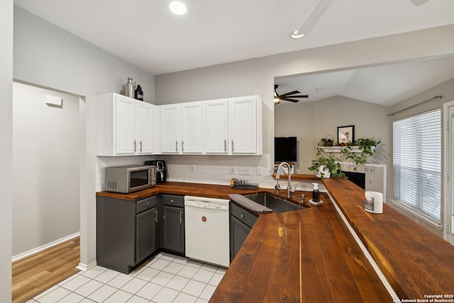 kitchen with butcher block countertops, sink, white dishwasher, white cabinets, and kitchen peninsula