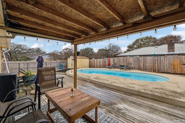 view of pool with a wooden deck and a storage shed