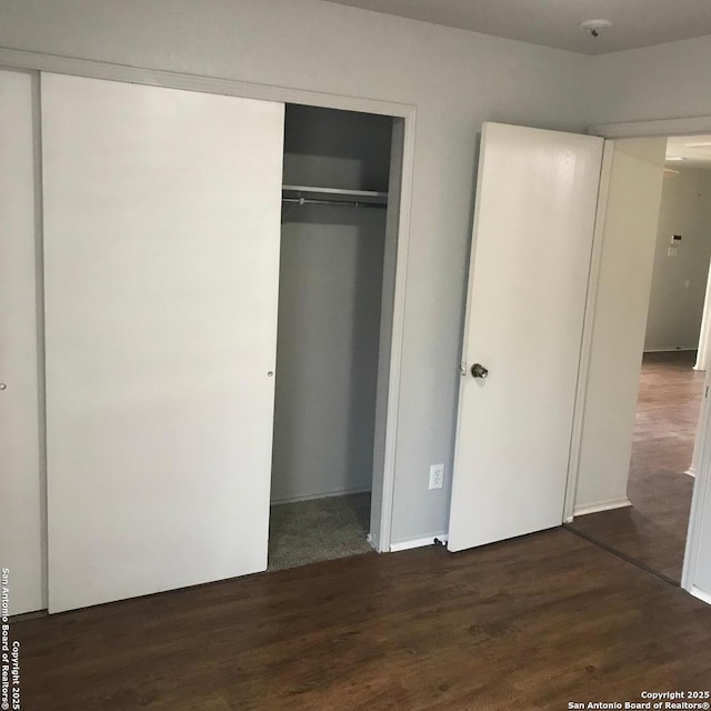 unfurnished bedroom with dark hardwood / wood-style floors and a closet