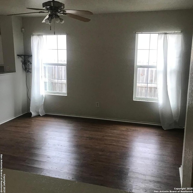 unfurnished room featuring ceiling fan, a wealth of natural light, and dark hardwood / wood-style flooring