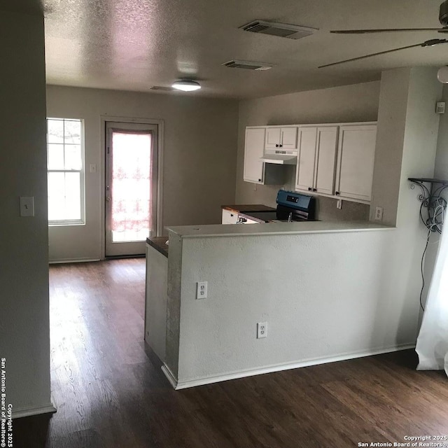 kitchen with dark hardwood / wood-style floors, kitchen peninsula, white cabinets, and stainless steel electric range