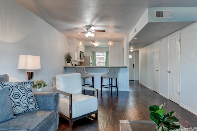 living room with ceiling fan, dark wood-type flooring, and a textured ceiling