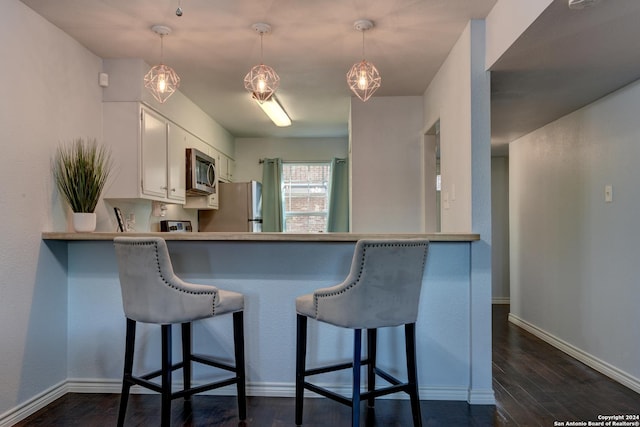 kitchen with stainless steel appliances, decorative light fixtures, kitchen peninsula, and white cabinets