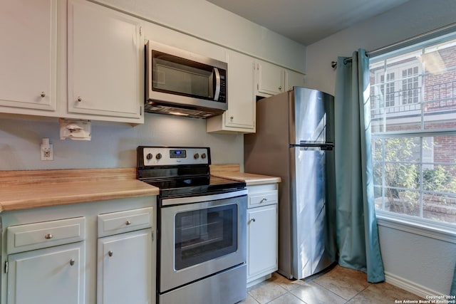 kitchen featuring stainless steel appliances, light tile patterned flooring, and white cabinets