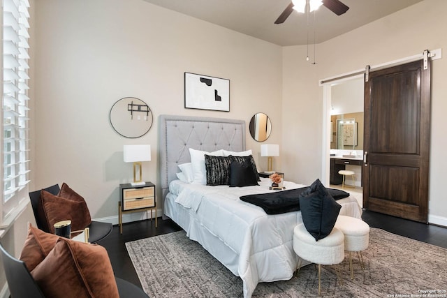 bedroom featuring a barn door, dark wood-type flooring, and ensuite bath