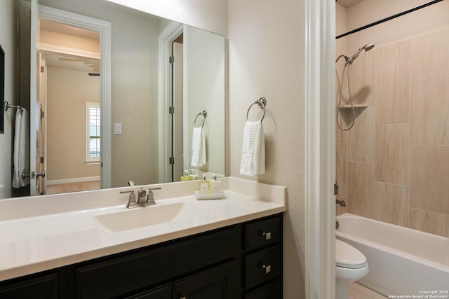 full bathroom with tiled shower / bath, vanity, and toilet