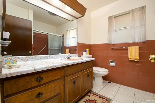 bathroom featuring toilet, a shower with shower door, tile walls, vanity, and tile patterned flooring