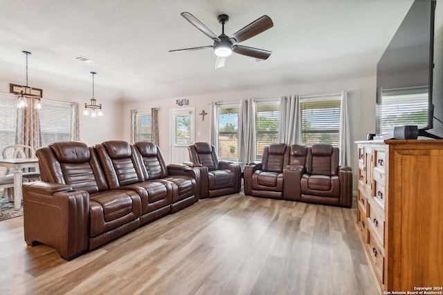 living room featuring ceiling fan with notable chandelier and light hardwood / wood-style flooring