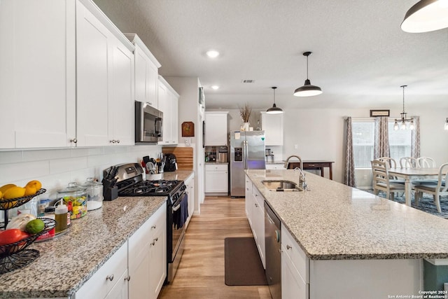 kitchen with stainless steel appliances, pendant lighting, and a center island with sink