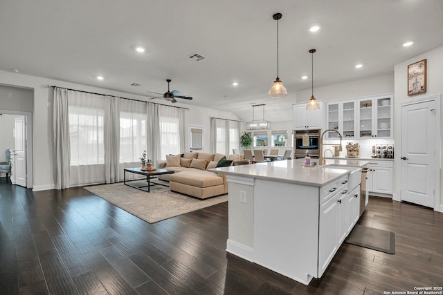 kitchen with pendant lighting, dark hardwood / wood-style floors, a center island with sink, and white cabinets