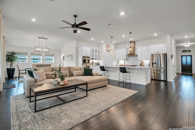 living room featuring dark hardwood / wood-style flooring, sink, and ceiling fan with notable chandelier