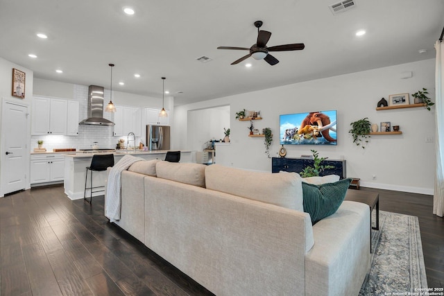 living room featuring dark wood-type flooring, ceiling fan, and sink