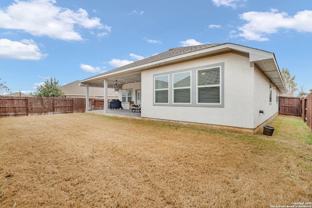 back of property featuring a lawn, a patio, and ceiling fan