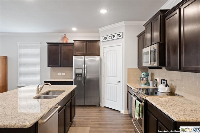 kitchen featuring an island with sink, appliances with stainless steel finishes, sink, and ornamental molding