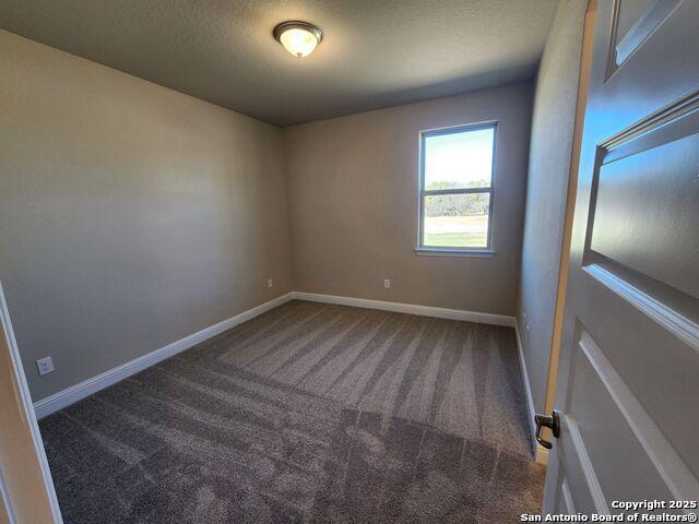 unfurnished room featuring a textured ceiling and carpet