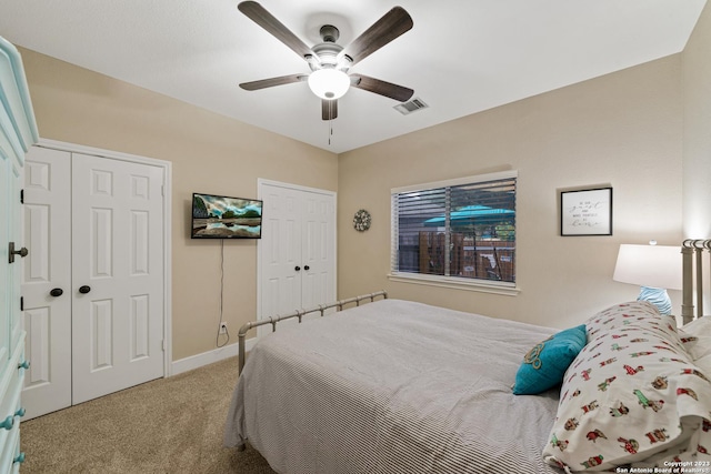 bedroom featuring multiple closets, light colored carpet, and ceiling fan