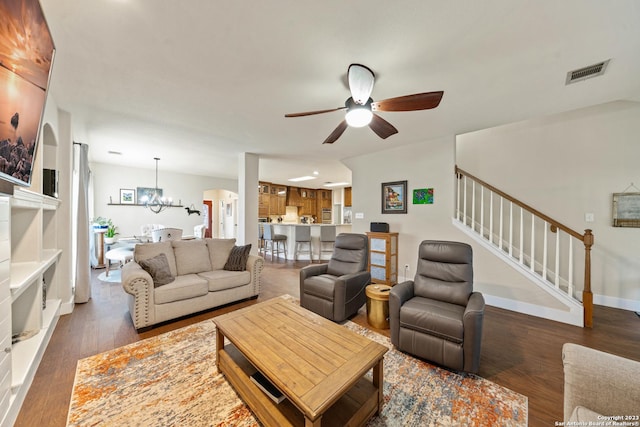 living room featuring dark wood-type flooring and ceiling fan with notable chandelier