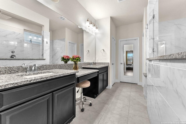 bathroom with tile patterned flooring, vanity, and tiled shower