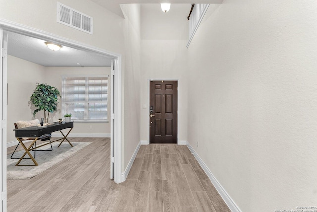 entrance foyer featuring a towering ceiling and light hardwood / wood-style floors