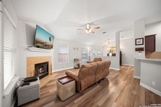 living room with lofted ceiling, a tile fireplace, light hardwood / wood-style floors, and ceiling fan