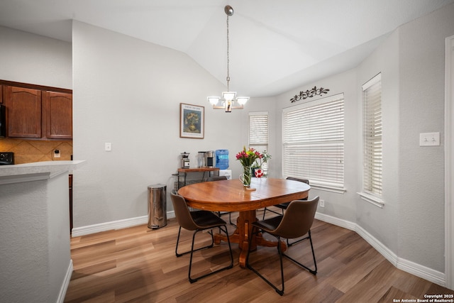 dining area featuring vaulted ceiling, a notable chandelier, and light hardwood / wood-style floors