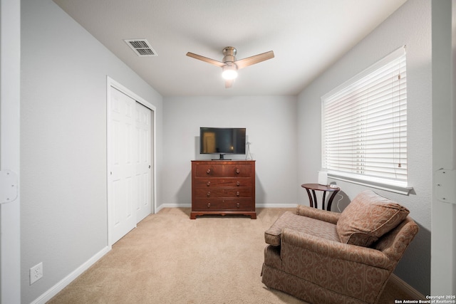 living area featuring light carpet and ceiling fan