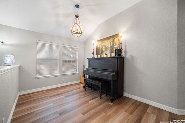 miscellaneous room with vaulted ceiling, wood-type flooring, and an inviting chandelier