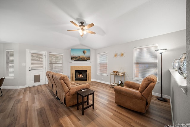 living room with a tiled fireplace, hardwood / wood-style flooring, lofted ceiling, and ceiling fan