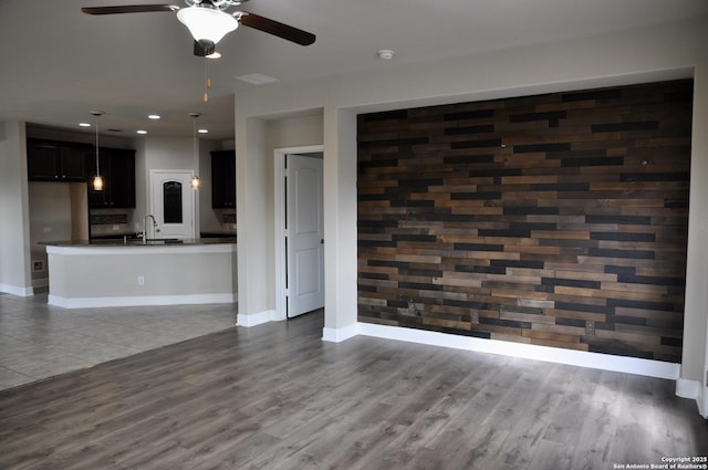 unfurnished living room with dark hardwood / wood-style flooring, sink, and ceiling fan