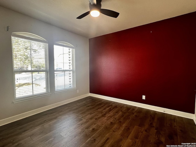 empty room with dark hardwood / wood-style floors and ceiling fan