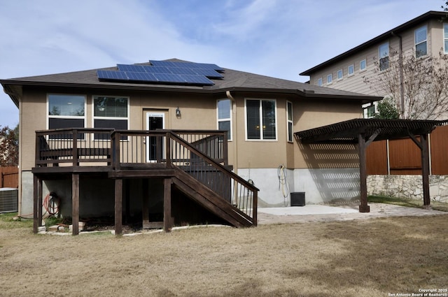 rear view of house featuring a wooden deck, a pergola, cooling unit, and solar panels