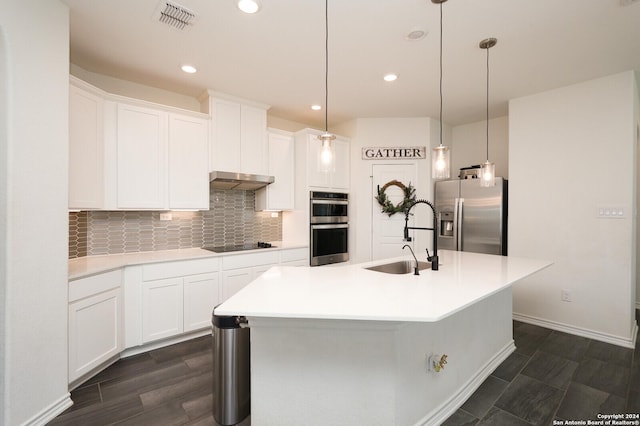 kitchen with appliances with stainless steel finishes, sink, white cabinets, hanging light fixtures, and a kitchen island with sink