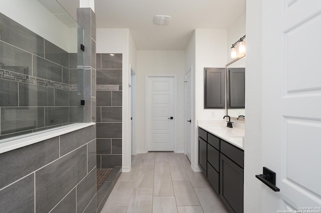 bathroom with tile patterned flooring, vanity, and a tile shower